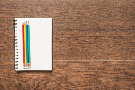 multicolor pencil with blank note book on wooden background, top viewの写真素材
