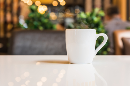 white coffee cup in coffee shop with bokeh light effectの写真素材