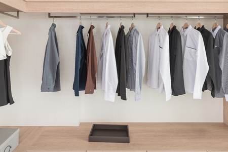 shirts hanging on rail in modern wooden wardrobe designの写真素材