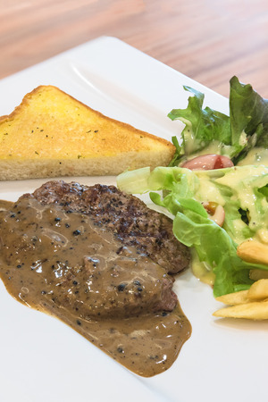 Grilled steak, French fries and vegetables on white plateの写真素材