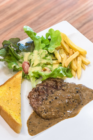 Grilled steak, French fries and vegetables on white plateの写真素材
