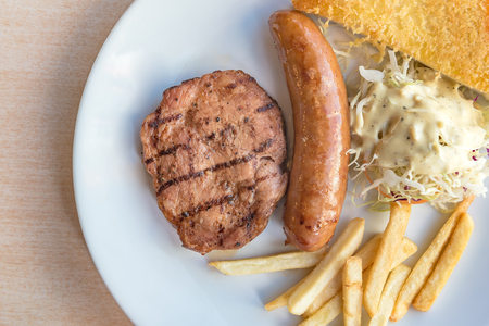 Grilled steak, French fries and vegetables on white plateの写真素材