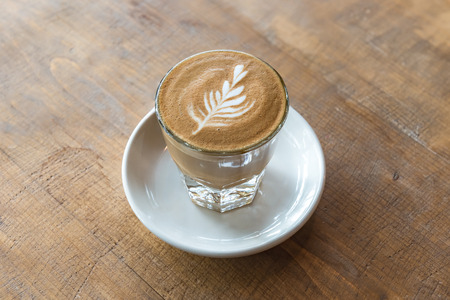 glass of latte coffee on wooden table in coffee shopの写真素材