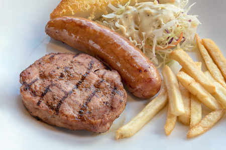 Grilled steak, French fries and vegetables on white plateの写真素材