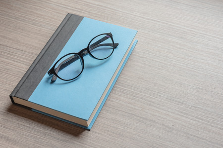 black glasses on blue notebook with wooden background