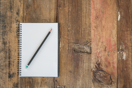 black pencil on white notebook with wooden backgroundの写真素材