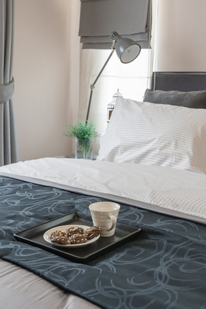modern bedroom design with white bed and tray of coffee cupの写真素材