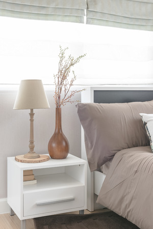 lamp and vase of flower on white table side in modern bedroom designの写真素材