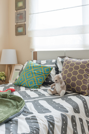 kid's bedroom with colorful pillows on white bed and modern lamp on wooden table sideの写真素材