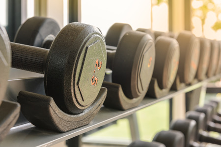 row of dumbbells in gym - vintage effect and sun flare filter effect