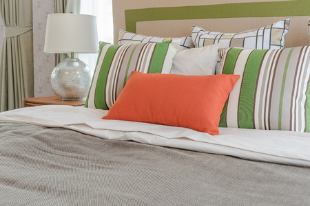 colorful pillows on white bed in modern bedroom design with white lampの写真素材