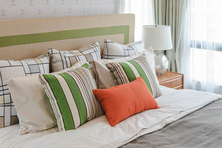 colorful pillows on white bed in modern bedroom design with white lampの写真素材