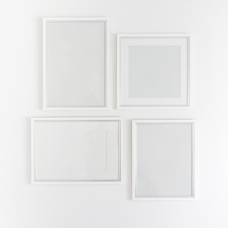 white blank picture frames hanging on white wallの写真素材