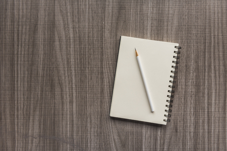 white pencil with blank notebook on wooden backgroundの写真素材