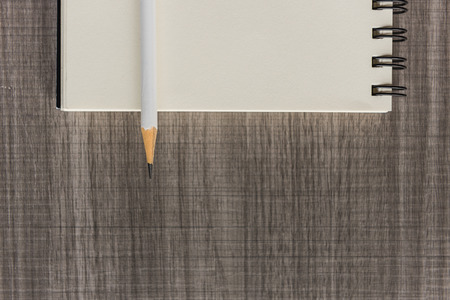 white pencil with blank notebook on wooden tableの写真素材