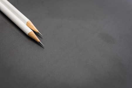 two white pencils on black backgroundの写真素材
