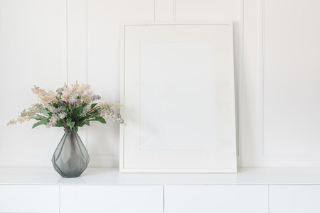 glass vase of flower with white picture frame on white tableの写真素材