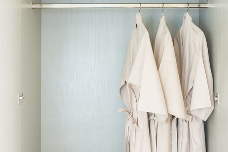 bathrobe hanging on rail in white wooden wardrobeの写真素材