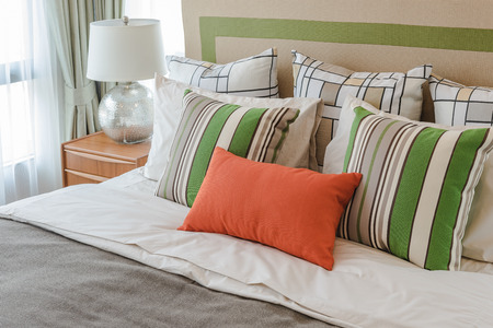 colorful pillows on white bed in modern bedroom design with white lampの写真素材