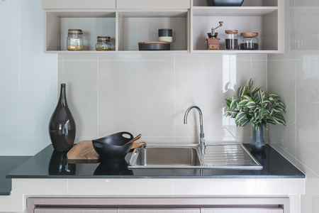 modern sink on black kitchen counter with vase of plantの写真素材