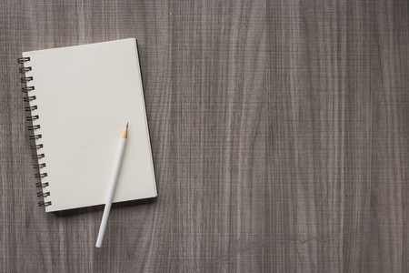 white pencil with blank notebook on wooden tableの写真素材