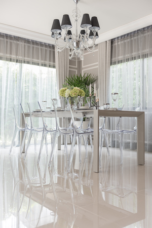 luxury dining room with translucent chair and vase of flowerの写真素材