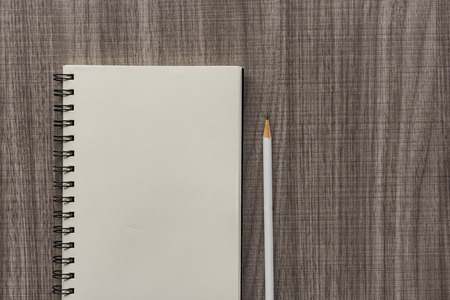 white pencil with blank notebook on wooden tableの写真素材