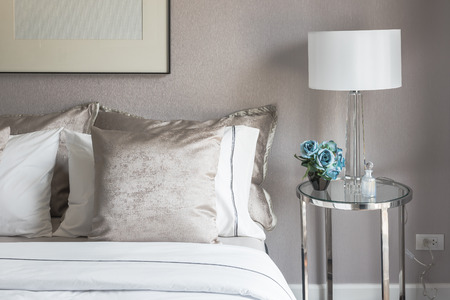 classic bedroom style with set of pillows on bed and white lamp on table sideの写真素材