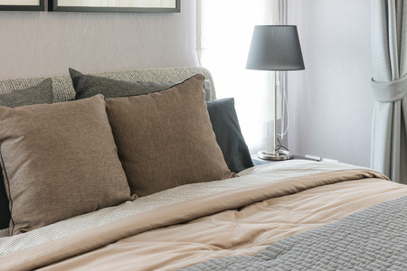 brown pillows on bed with black lamp in modern bedroom designの写真素材