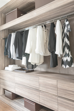 black and white color tone clothes hanging in wooden closetの写真素材