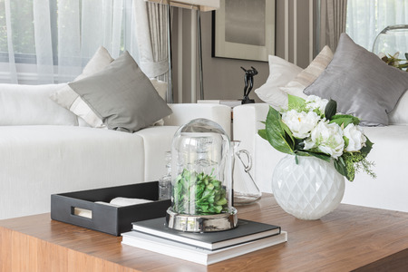 luxury white sofa with pillows set in living room with vase of flower on wooden tableの写真素材
