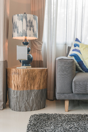 set of pillows on modern grey sofa in living room with lamp on wooden table sideの写真素材
