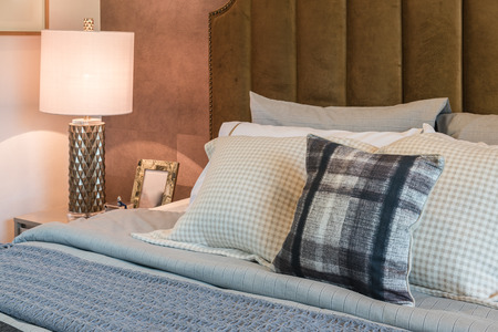 luxury bedroom with set of pillows on bed and white lamp on table sideの写真素材