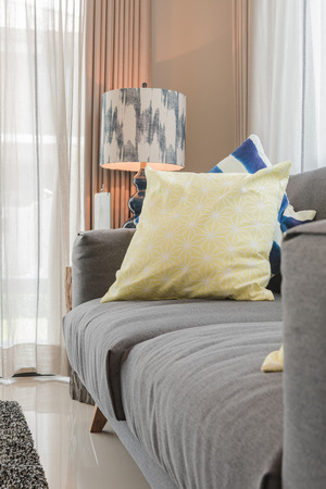 set of pillows on modern grey sofa in living room with lamp on wooden table sideの写真素材