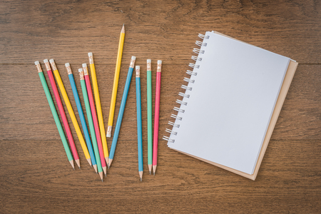 multicolor pencils and blank notebook on wooden background with copy spaceの写真素材