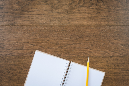 blank white notebook on wooden texture background with yellow pencilの写真素材