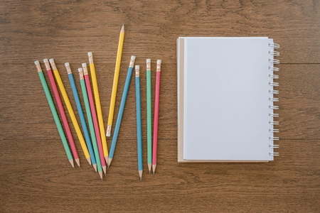 multicolor pencils and blank notebook on wooden background with copy spaceの写真素材