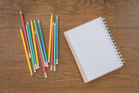 multicolor pencils and blank notebook on wooden background with copy spaceの写真素材