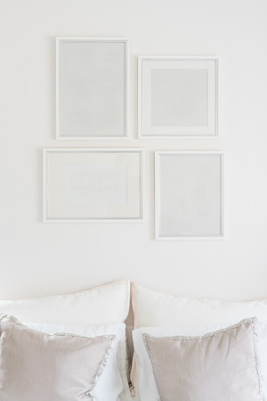 white blank picture frames hanging on white wallの写真素材