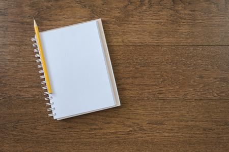 blank white notebook on wooden texture background with yellow pencilの写真素材