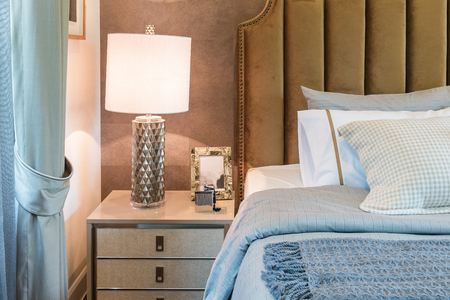 luxury bedroom with set of pillows on bed and white lamp on table sideの写真素材