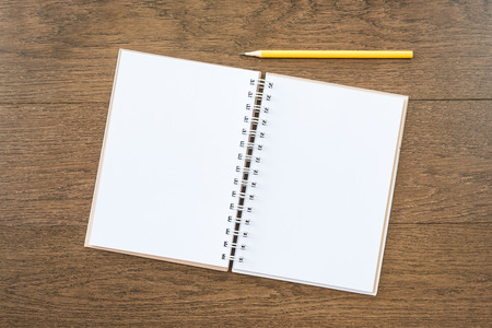 blank white notebook on wooden texture background with yellow pencilの写真素材