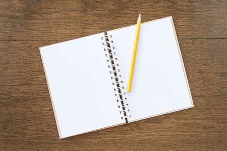 blank white notebook on wooden texture background with yellow pencilの写真素材