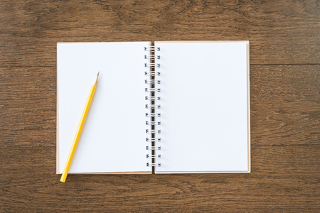 blank white notebook on wooden texture background with yellow pencilの写真素材