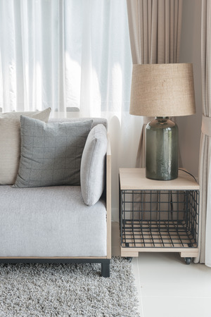 modern grey sofa with pillows and modern lamp on table side in living room designの写真素材