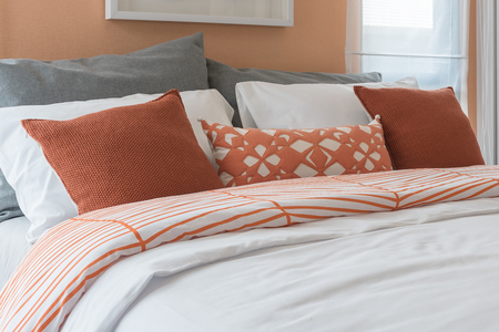 orange color tone pillows set on bed in modern bedroom designの写真素材