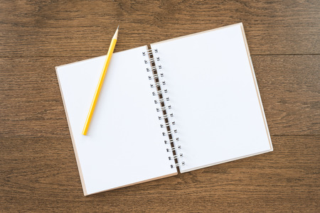 blank white notebook on wooden texture background with yellow pencilの写真素材