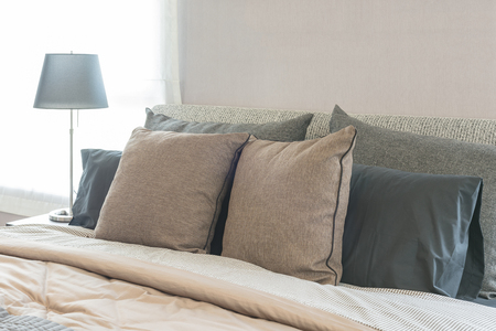 set of pillows on modern bed in bedroom design with lampの写真素材
