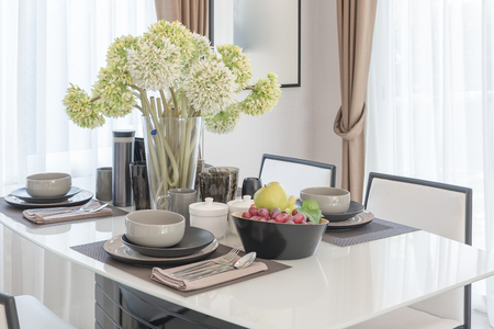 table set on dining table with vase of flower in dining roomの写真素材