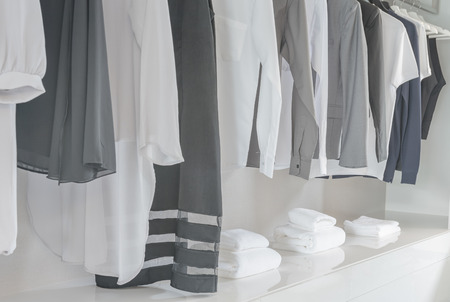 black and white color tone clothes hanging on rail in white closetの写真素材